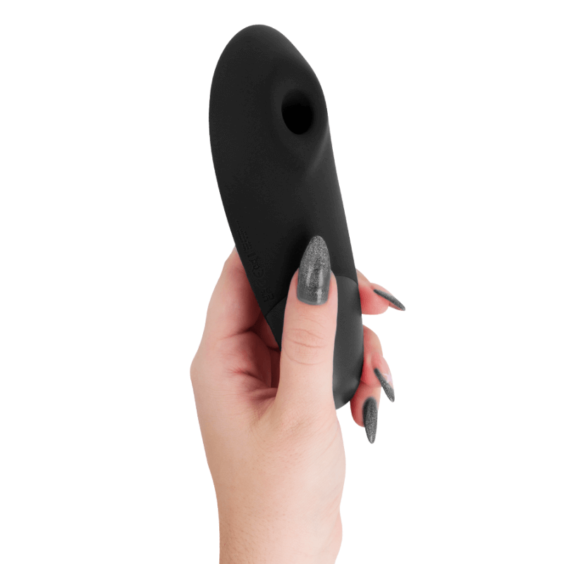 Sextoy noir en forme ovale, tenu par une main féminine, design lisse à pointe arrondie et petit renflement.